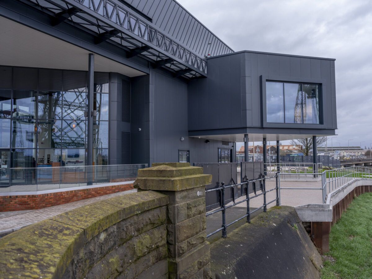 Glazed elevation of the visitor centre, with the steelwork of Newport Transporter Bridge visible beyond the glass.